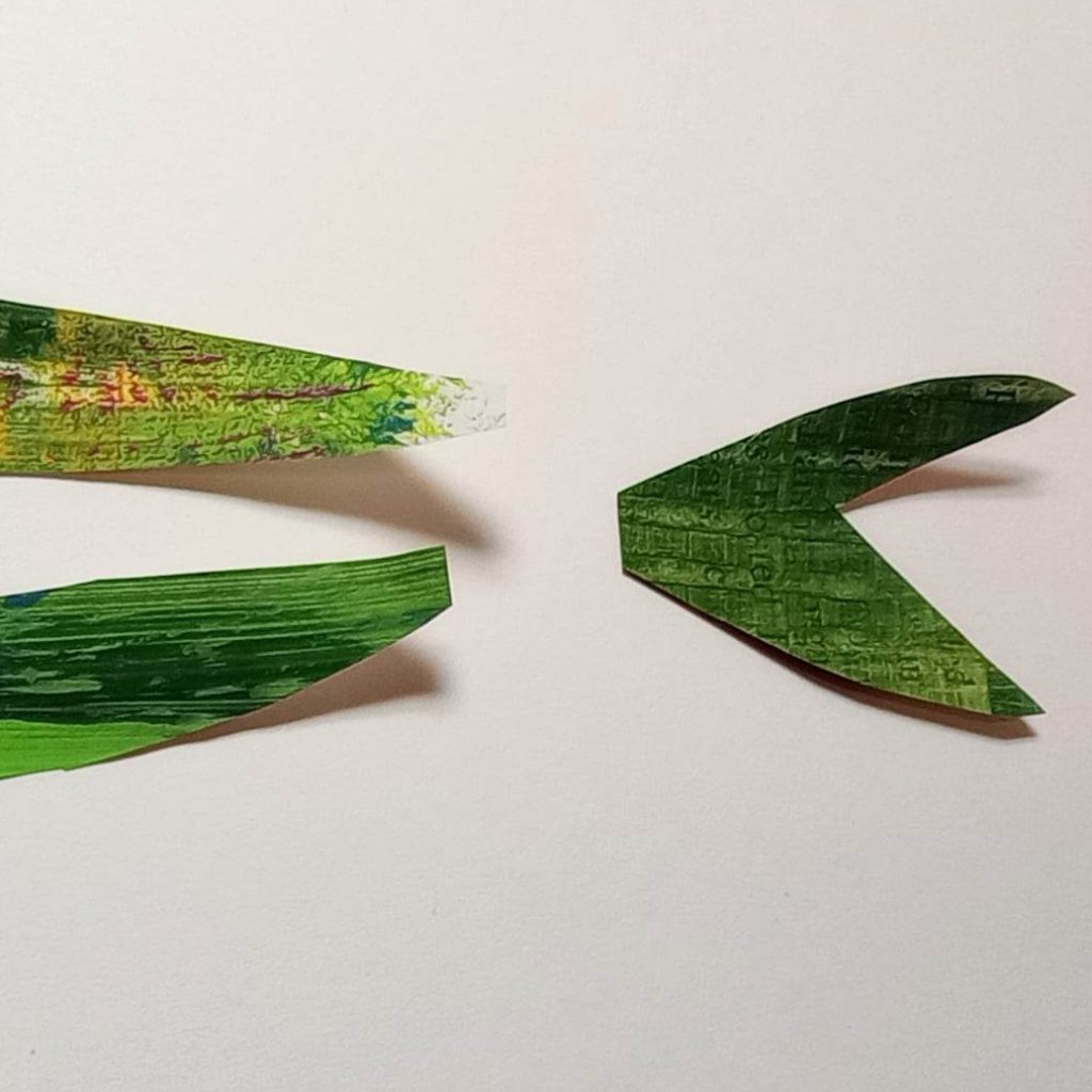 Tail piece of my cut paper fish in Eric Carle style. Green with stripes, with a bit of newspaper print showing through.